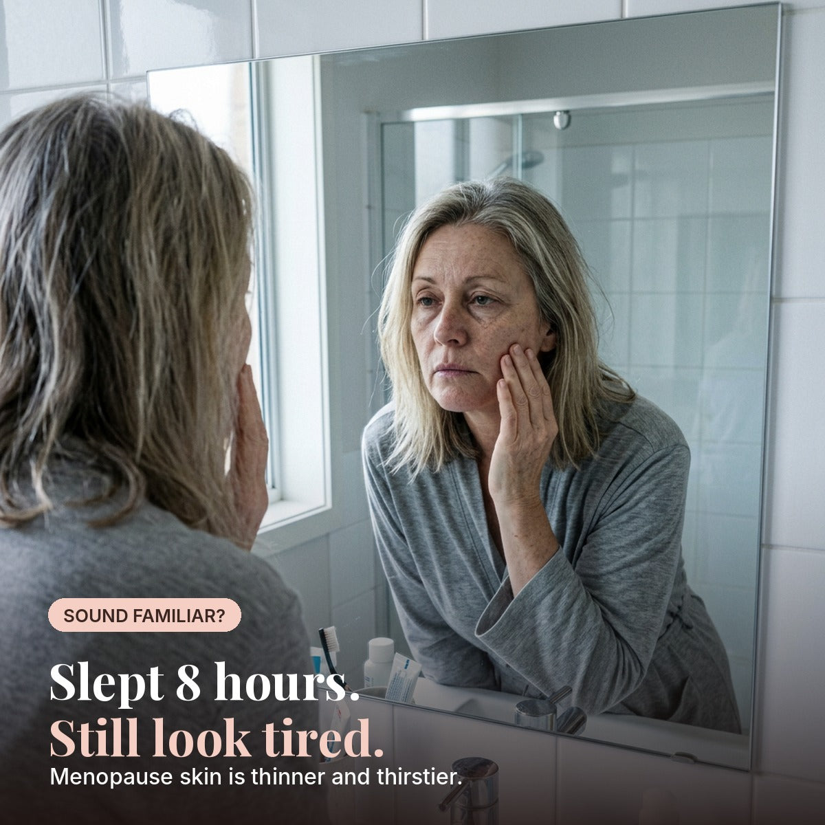 Woman in her 50s looking tired in the bathroom mirror. Menopause skin is thinner and thirstier.
